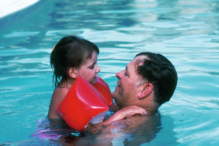 Father and Daughter in a Pool. A 10 year-old Caucasian girl with her father in a swimming pool. She was diagnosed at age three with a form of Acute Lymphoblastic Leukemia (ALL) that did not respond to therapy. She is presently in long-term remission after an experimental bone marrow transplant was performed. She now suffers from chronic GVH (Graft Versus Host Disease) which is rare.